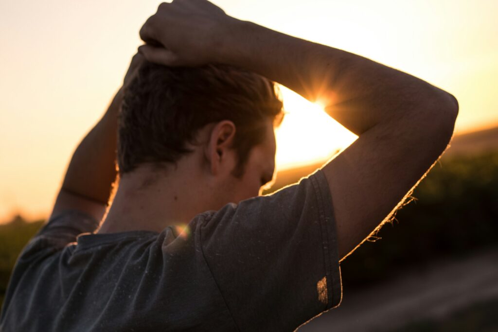 Picture of a man looking down with hands on his head, appearing worried